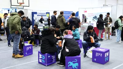 Studierende sitzen in der Lounge der Messehalle. Totale. 