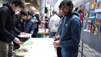 Besucher*innen bedienen sich am Essensstand von Studierenden aus Nepal. 