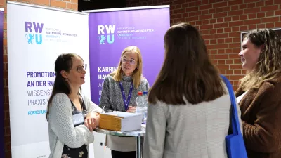 Mehrere Personen stehen an einem Messestand und unterhalten sich. 