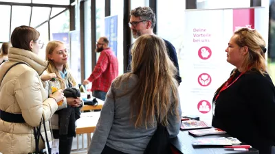 Mehrere Personen stehen um einen Messestand und unterhalten sich. 