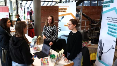 Mehrere Personen stehen an einem Messestand. 