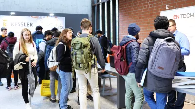 Studierende stehen vor Messeständen im Foyer des Hauptgebäudes. Halbtotale Einstellung.