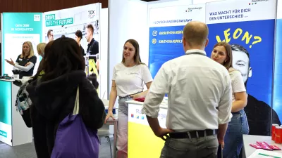 Mehrere Studierende informieren sich an einem Messestand. Amerikanische Einstellung. 