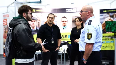 Eine Person lässt sich an einem Messestand beraten. Amerikanische Einstellung.