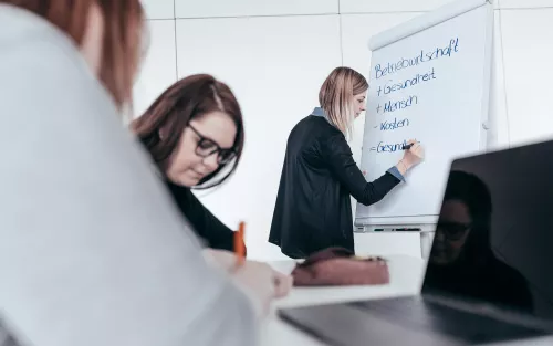 Studentin schreibt an Flip Chart.