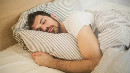 Junger Mann schläft im Bett