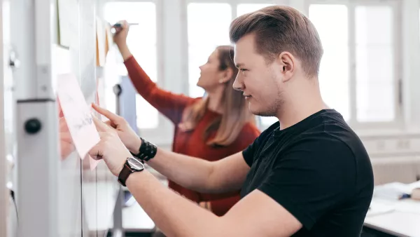 Zwei Studierende schreiben hintereinander auf Flip Charts.