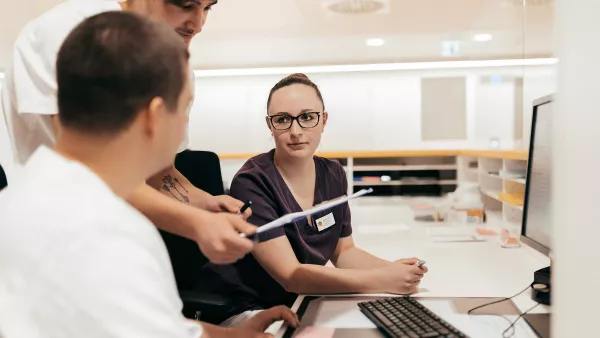 drei Studierende besprechen sich im Pflegebüro