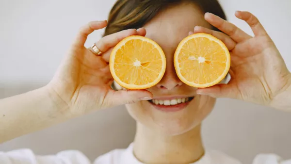 Eine junge Frau hält sich Orangenscheiben vor die Augen